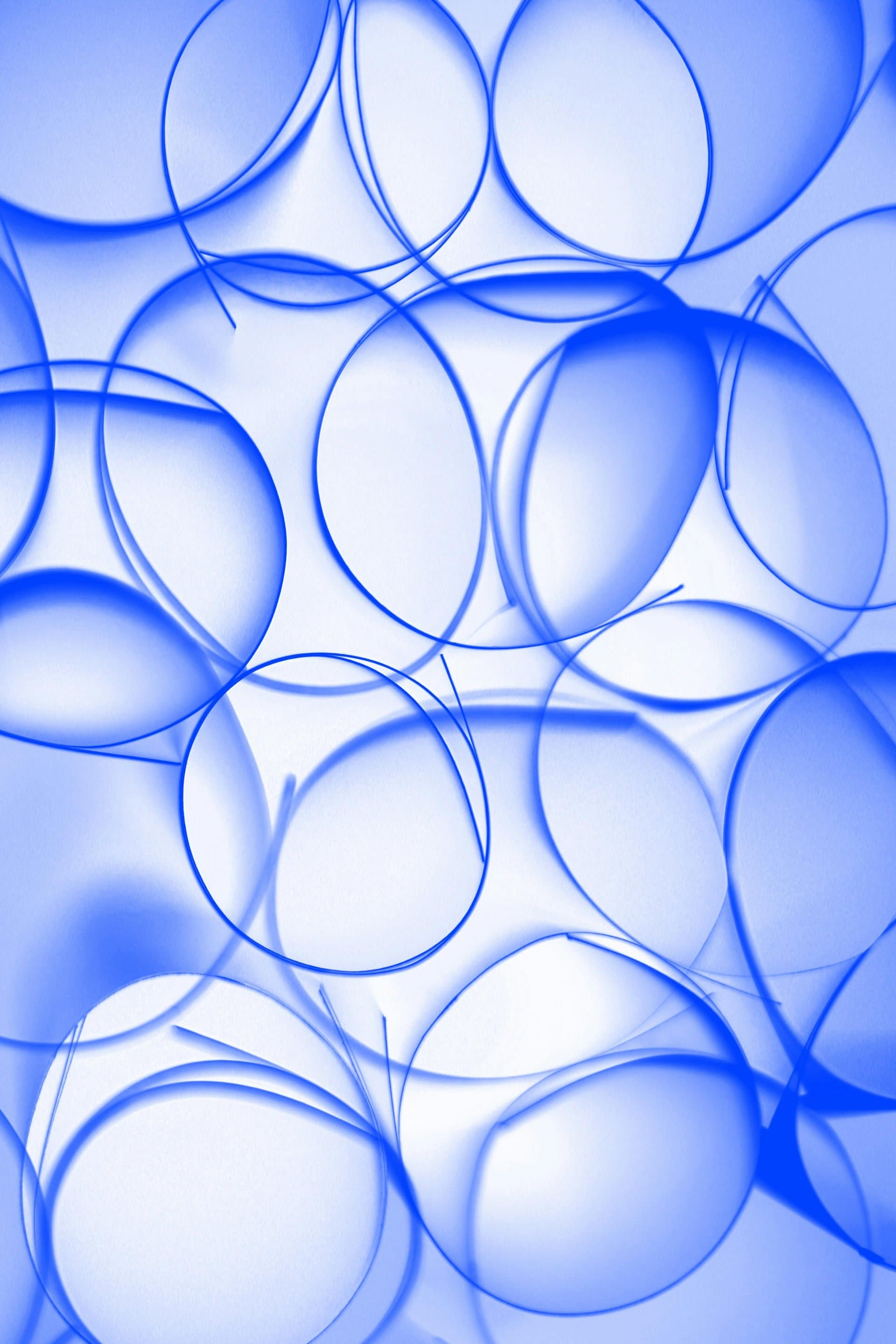 Abstract image of overlapping translucent blue circles on a light background, evoking laboratory glassware and clinical research aesthetics.